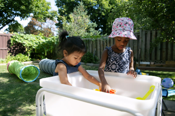two children enjoying sensory water play in a home child care providers garden in the summer