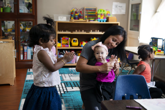 licensed home child care provider interacting with an infant and children in her care